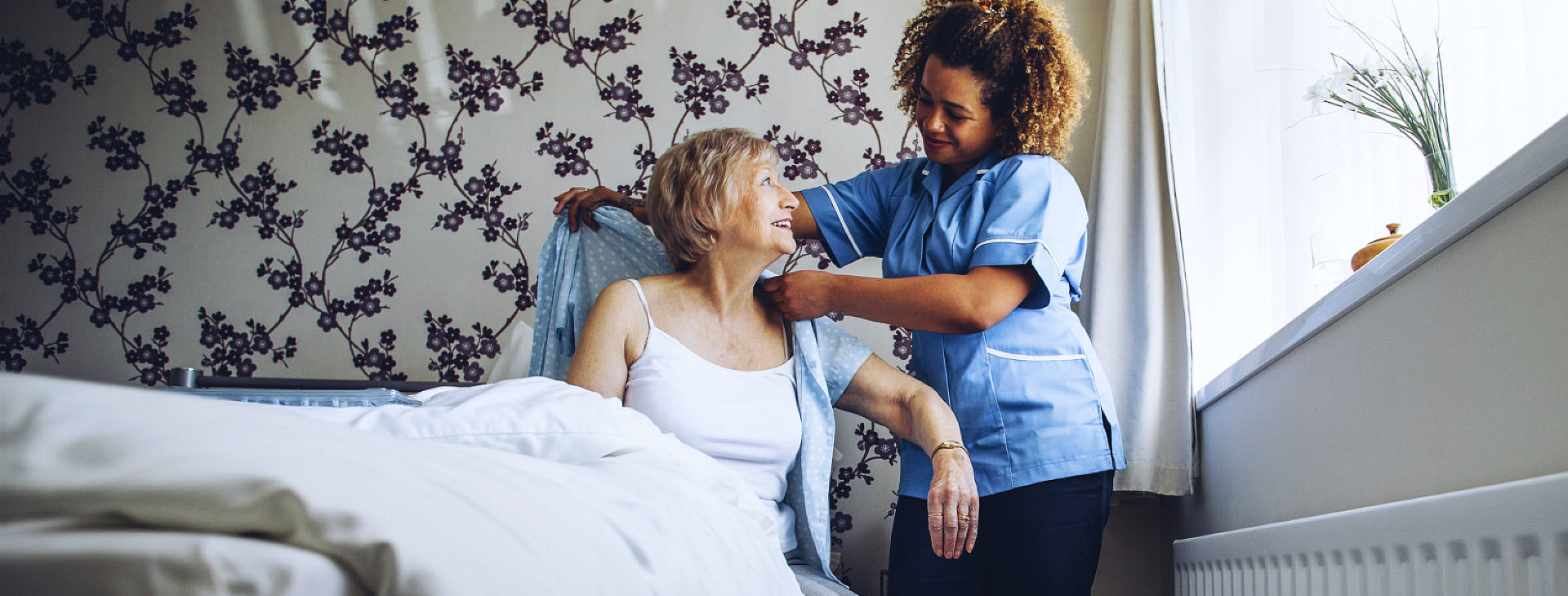 caregiver helping senior woman get dressed