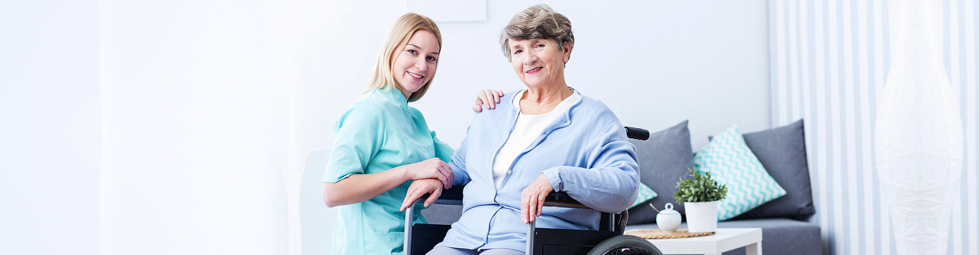 smiling senior woman on wheelchair with her caregiver